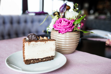 Creamy cheesecake with chocolate cookies and cream biscuits. Oreo cake and a beautiful vase with flowers on the table. A beautiful bouquet of flowers from roses and tulips.