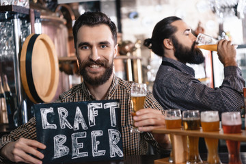 Two bearded men taste a beer of different styles in beer samplers in brewery of craft beer.