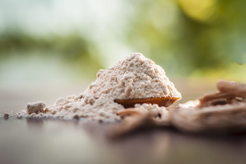 Ayurvedic herb satavari,Asparagus racemosus with its powder and root in a bowl on brown wooden surface in dark gothic colors for healthy female reproductive system, for an good reproductive system.