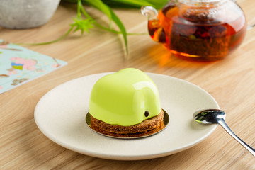Mini mousse cake apple shaped covered with green mirror glaze on plate