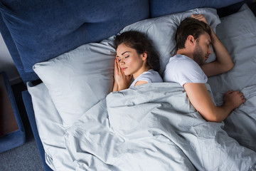 Fototapeta na wymiar Young couple sleeping in bed in modern bedroom