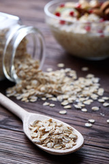 Composition with bowl of oatmeal porrige and dry oatmeal in glassware on vintage wooden table, selective focus