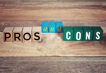 Fototapeta premium Conceptual - ‘PROS and CONS’ written on wooden blocks on a wooden table.