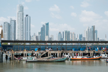 Obraz premium Fishermen and boats on fish market / harbour with city skyline, Panama City