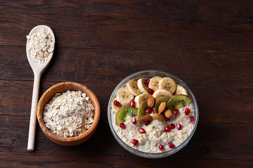 Diet breakfast oatmeal with fruits, bowl and spoon with oat flakes, selective focus, close-up