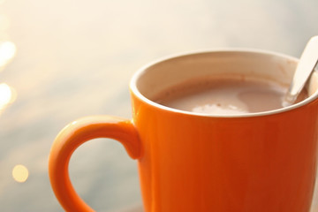 Morning hot coffee cup with spoon close up on water bokeh background