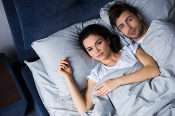 Young man and woman embracing while lying in bed