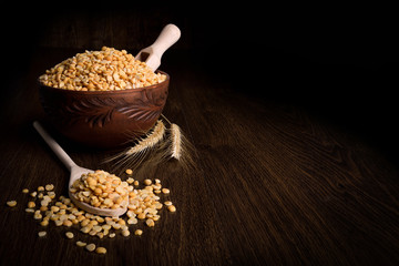 Сhopped peas in a wooden bowl on a wooden background near the ears of wheat. wooden spoon with chopped peas