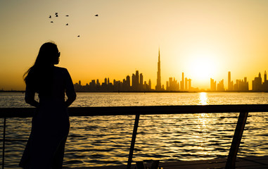 Woman facing panoramic view of Dubai at sunset
