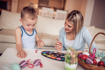 Obraz na płótnie Canvas Mother and her son painting eggs