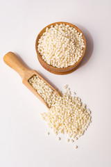 Sago in a wooden bowl and in a wooden scoop on a white background.