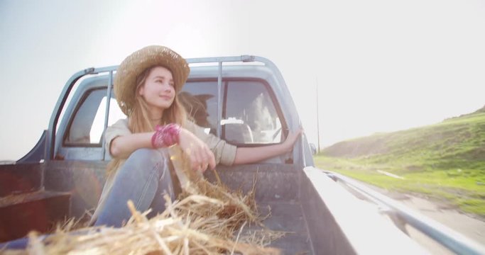 Young woman travelling in the back of a pick-up truck