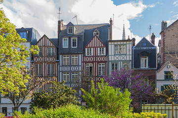 Picturesque half-timbered facades of old houses surrounded with flowering trees in historical center of Rouen in the fine spring evening, Normandy, France
