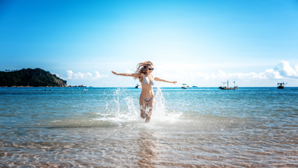 Attractive young woman with long blond hair running down the beach, relaxing and vacation in the seaside resort