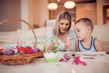 Obraz na płótnie Canvas Portrait of little boy and mother coloring eggs for Easter