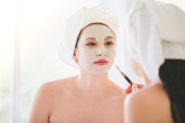 Beautiful young woman and friend spa applying cosmetic mask cream on face relaxing receiving massage,Spa face concept