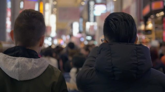 International friends walking down busy shopping street in Osaka, Japan.
