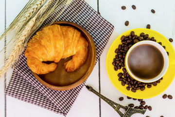 top view coffee and croissant with coffee bean. Rustic white wooden background with copy space