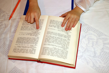 Naklejka premium Female hands holding a big book, on a white table, reading,