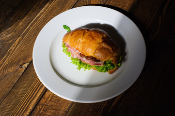 Fresh croissant with ham and salad