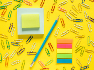 Business flat lay with copy space pencil, Notepad Stationery colored paper clips on colorful yellow background