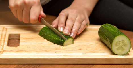 Slicing cucumber with a knife on the board