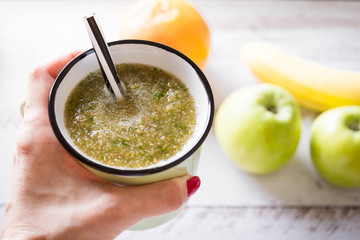 Green smoothies made from apples, parsley, banana in  a transparent glass in female hands. The concept of healthy eating. Weight Loss Drink. Close up