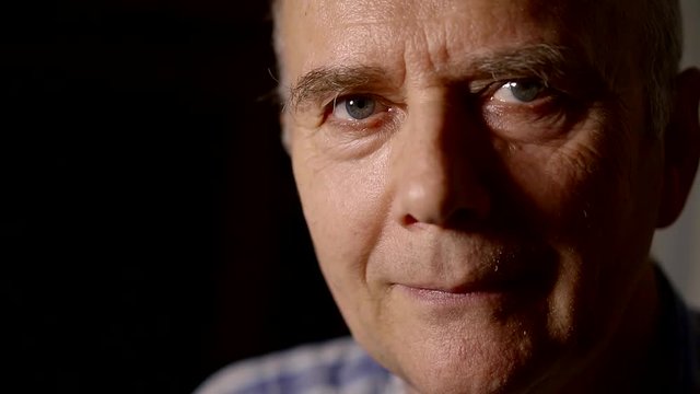 close-up portrait of an elderly man in a dark room