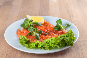 salted salmon with a slice of lemon on a sheet of green salad