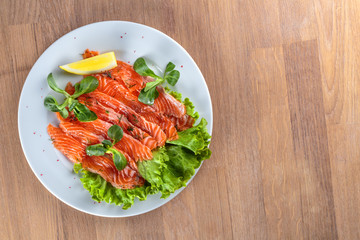 salted salmon with a slice of lemon on a sheet of green salad