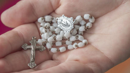 hand holding a rosary with a Catholic crucifix and Mary, a holy mother of God - obrazy, fototapety, plakaty