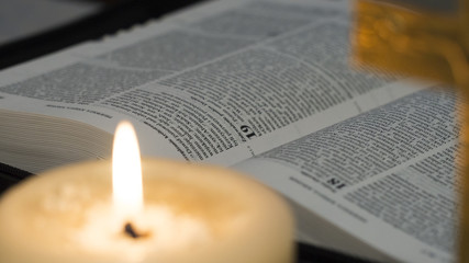 open Bible next to a lit candle