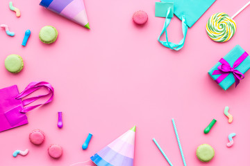 Birthday party accessories. Party hat, sweets, paper bag for gift on pink background top view copy space mockup