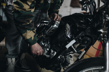 Fototapeta premium Young man doing hard job in car and motorcycle repair shop.