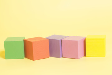 Obraz premium Coloured wooden cubes on yellow background