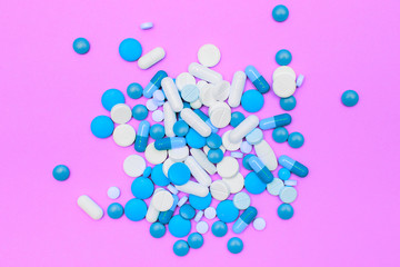 drugs capsules and pills on pink background.