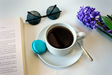 Coffee Cup and spring flower hyacinth, sunglasses, book on white table. Selective focus.