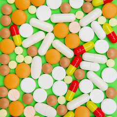 drugs capsules and pills on green background