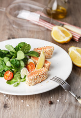 salad with salmon grilled in sesame seeds, cherry tomatoes and quail egg on wooden table