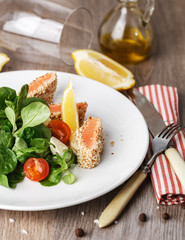 salad with salmon grilled in sesame seeds, cherry tomatoes and quail egg on wooden table