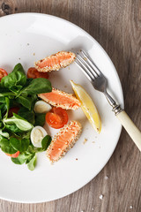 salad with salmon grilled in sesame seeds, cherry tomatoes and quail egg on wooden table