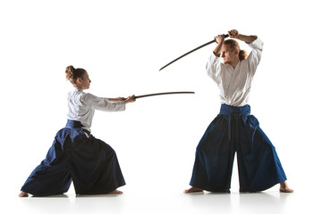 Man and woman fighting and training aikido on white studio background