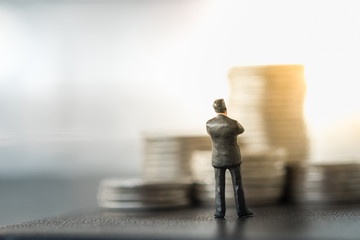 Business, Money and planning concept. Businessman miniature figure standing and looking to stack of...