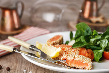 salad with salmon grilled in sesame seeds, cherry tomatoes and quail egg on wooden table
