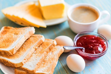 Breakfast with coffee, eggs, toasts, cheese, jam