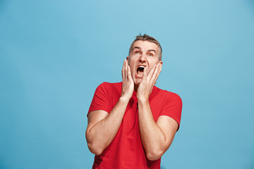 The young attractive man looking suprised isolated on blue