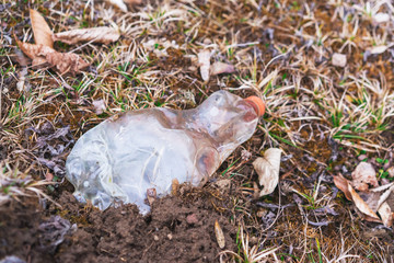 Contamination of the environment by humans. Plastic bottle thrown on the garbage on the meadow