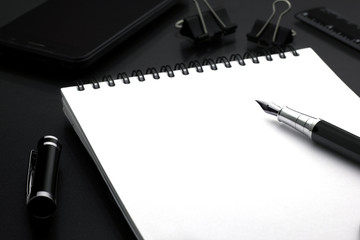 black pen pen lies on a white wicker book in the background phone, ruler, paperclips. business © marrypopins