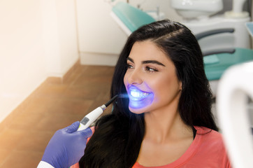 Gorgeous young woman UV lamp teeth whitening treatment 