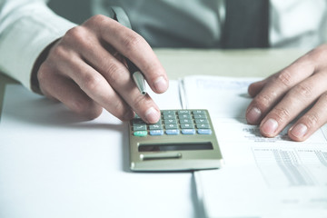 Businessman using calculator in his desk.